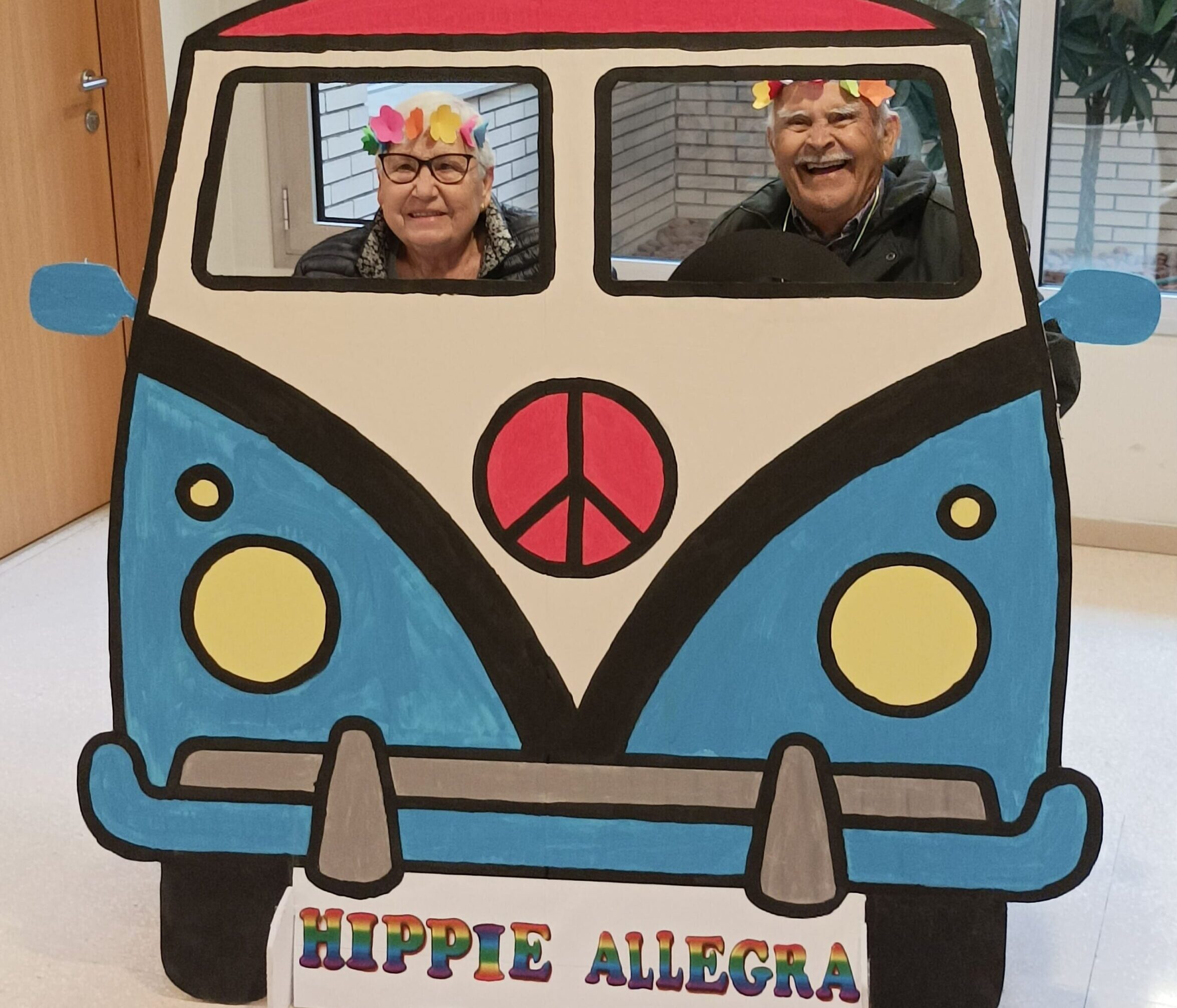 Residentes posan felices ante la cámara tras un photocall de coche hippie confeccionado para la fiesta de Carnaval