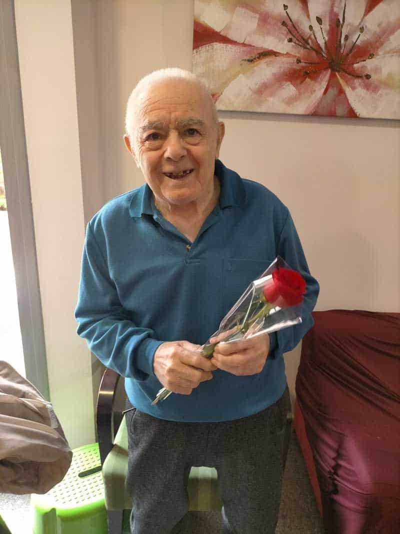 Residente posa sonriente con su rosa regalada el día de su cumpleaños
