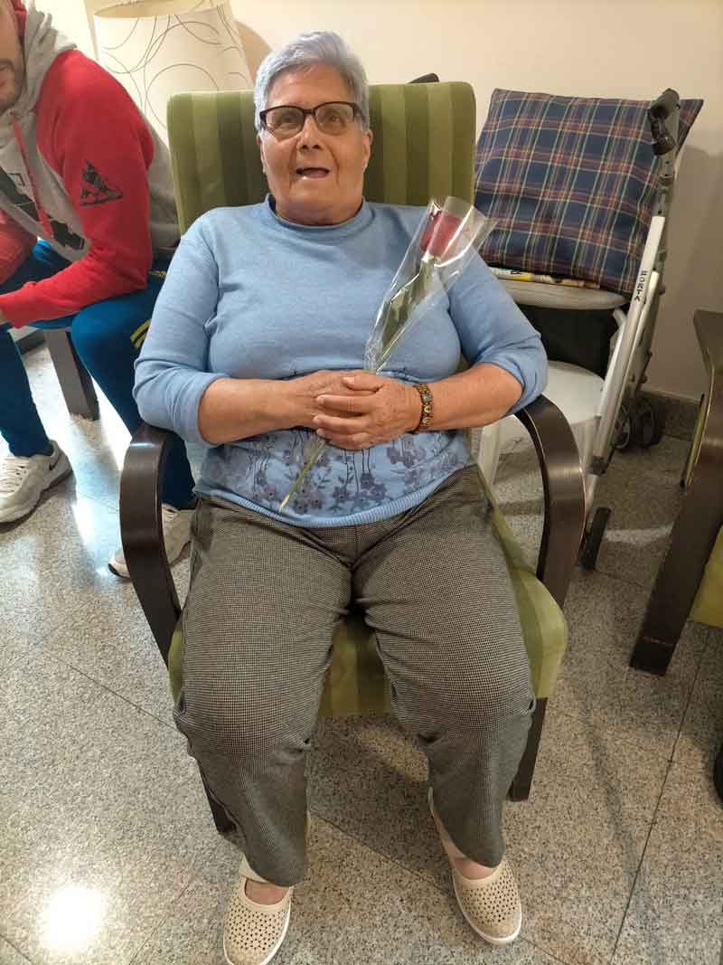 Residente posa sonriente con su rosa regalada el día de su cumpleaños
