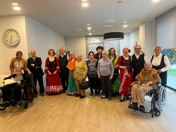 Residentes posan sonrientes para la foto junto al grupo de baile de sevillanas que les visita