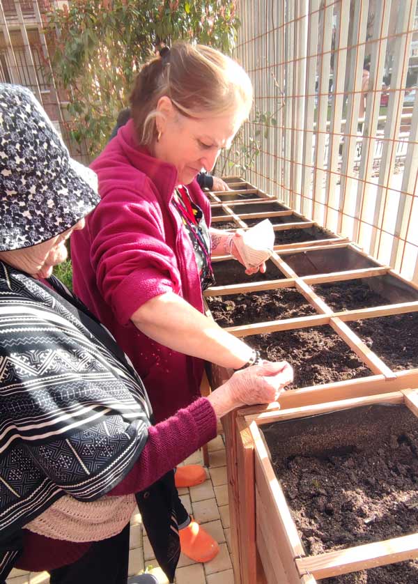 Monitora enseña a residente como plantar alimentos en el huerto