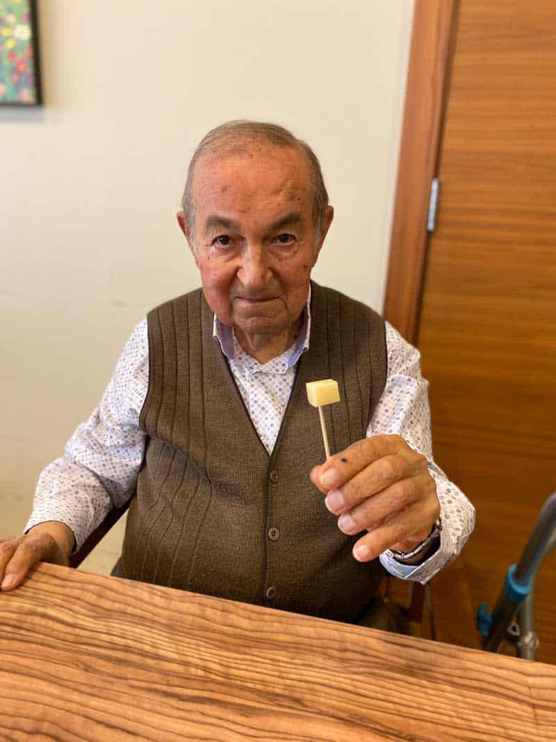 Residente posa sonriente con una tapa de queso