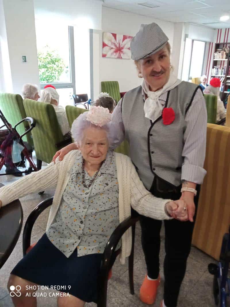 Residente y cuidadora posan vestidas con el traje típico de San Isidro