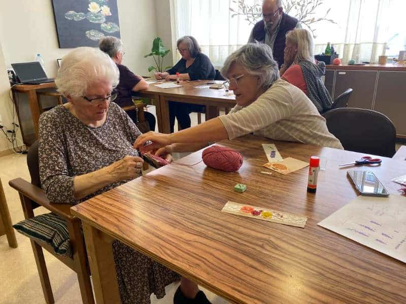 Una familiar ayuda a realizar una manualidad a una residente de Sabadell-Allegra