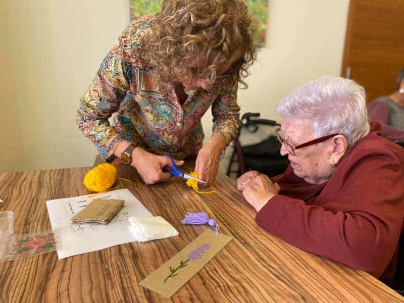 Residente y familiar recortan una pieza con la que van a realizar un punto de libro