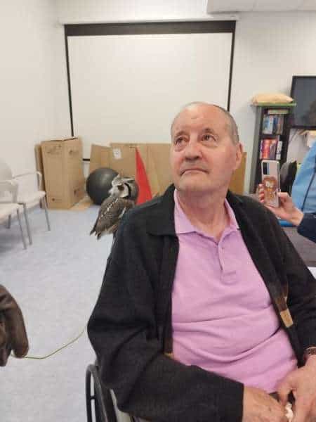 Residente sostiene en un hombro a un pájaro de terapia