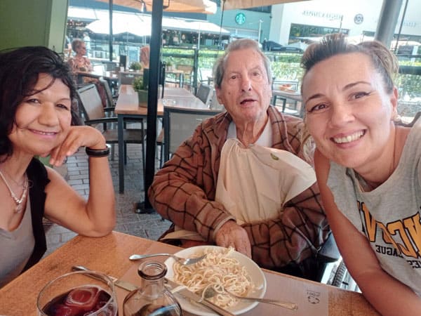 Auxiliares y residente sonríen a la cámara durante una comida