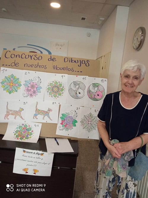 Una residente posa junto al panel del concurso de dibujos
