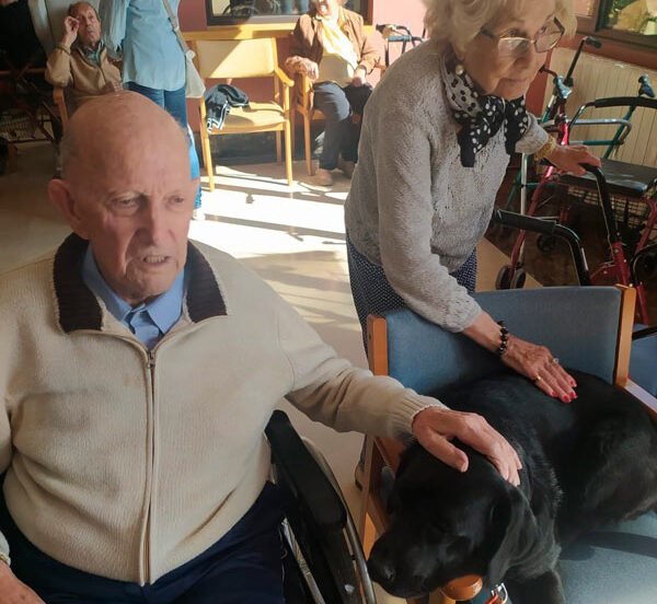 Residentes posan sonrientes junto al perro de terapia