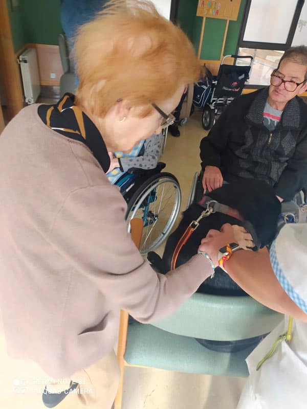 Una residente ayuda a otra a acariciar al perrito