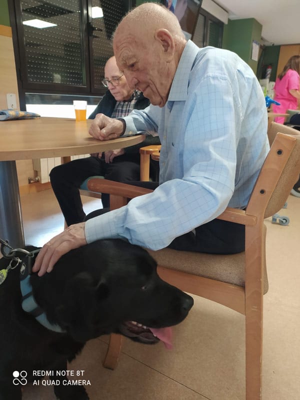 Otro residente feliz mientras acaricia al perro de la terapia