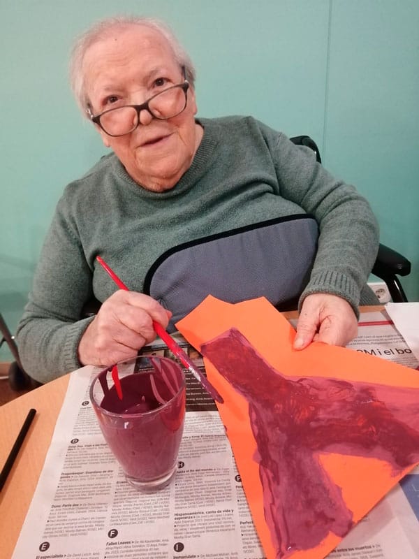 Residente sonríe a cámara mientras muestra su dibujo