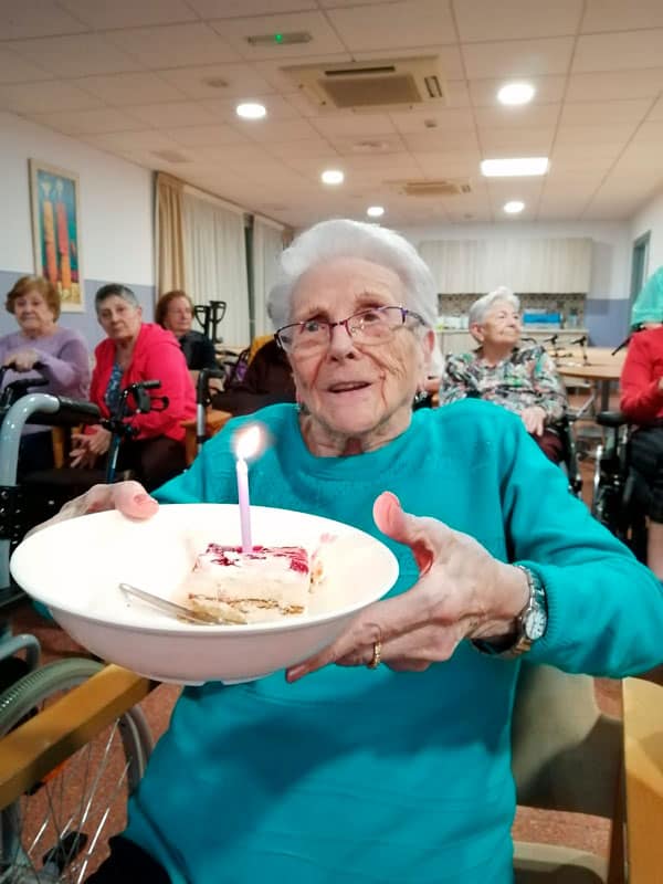Una residente muestra orgullosa su trozo de pastel de cumpleaños