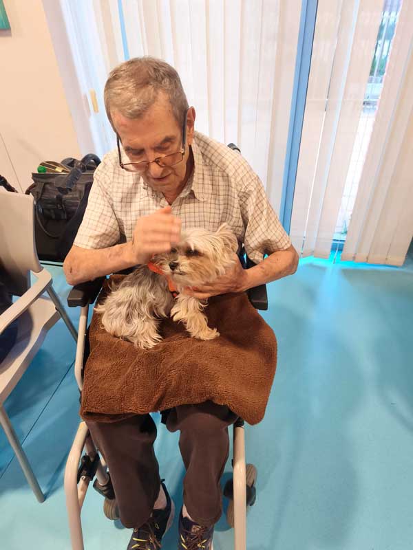 Un residente posa junto a un perro de terapia