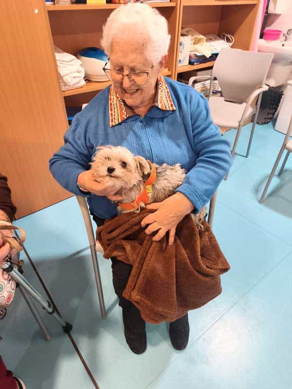 Una residente feliz junto al perro de terapia
