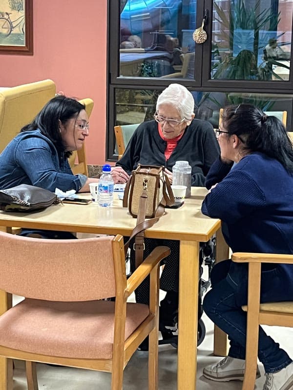 Una residente mantiene una conversación junto a familiares y auxiliares
