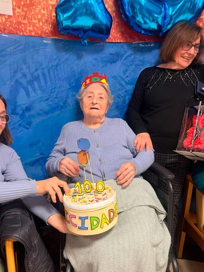 Residente junto al pastel de su cumpleaños número 100
