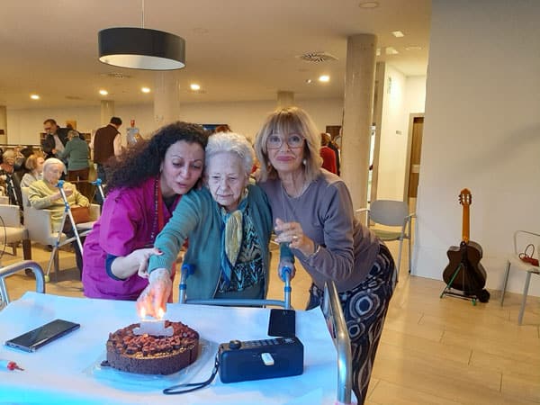 Residente sopla las velas junto a una familiar y una auxiliar