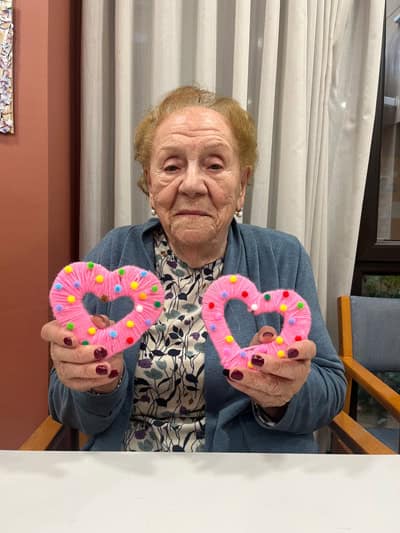 Una residente posa junto a una manualidad de corazones