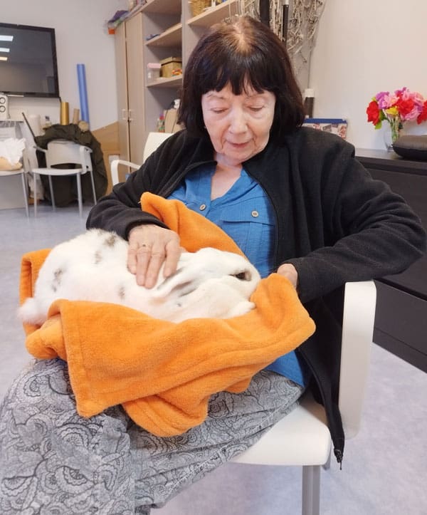 Residente acaricia a un conejo en la sesión de terapia con animales
