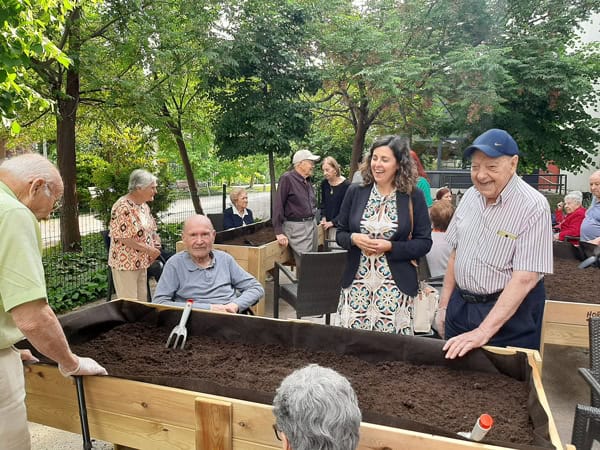 Residentes y trabajadores de la residencia ríen mientras trabajan en el huerto
