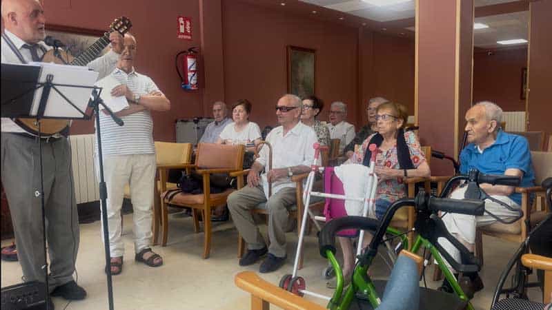 Los asistentes del centro escuchan atentos la actuación del grupo local