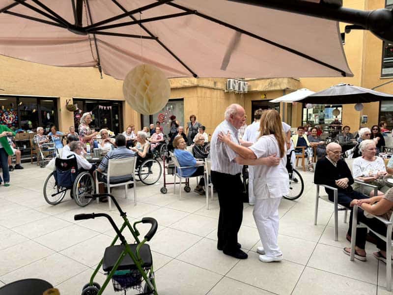 Un residente baila con una auxiliar durante la fiesta de bienvenida del verano