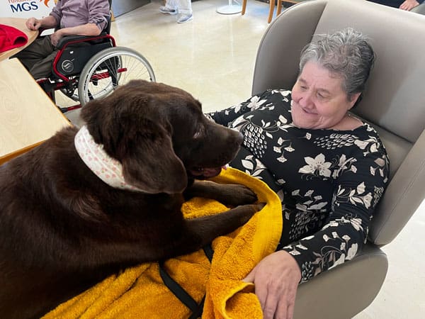 Una residente feliz con el perrete de terapia