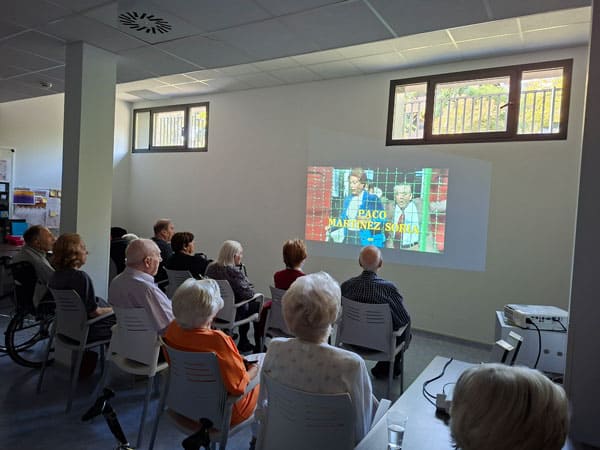 Personas mayores viendo una presentación en una sala moderna y luminosa en MGS Seniors.