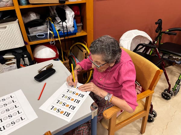 Una residente pinta una hoja con letras