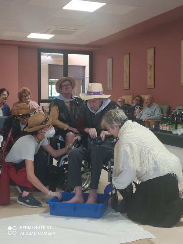 Cuidadoras ayudan a un residente a pisar uva durante la vendimia