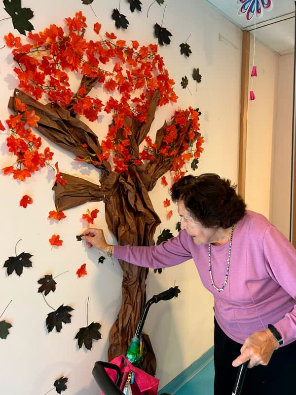 Una residente decora el árbol de otoño