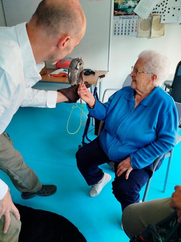 Una residente, feliz, acaricia a un buho de terapia