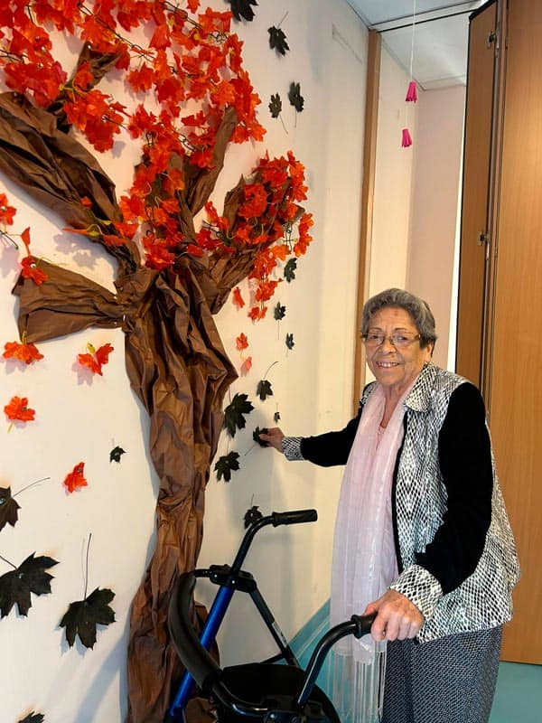 Una residente feliz junto al árbol de otoño