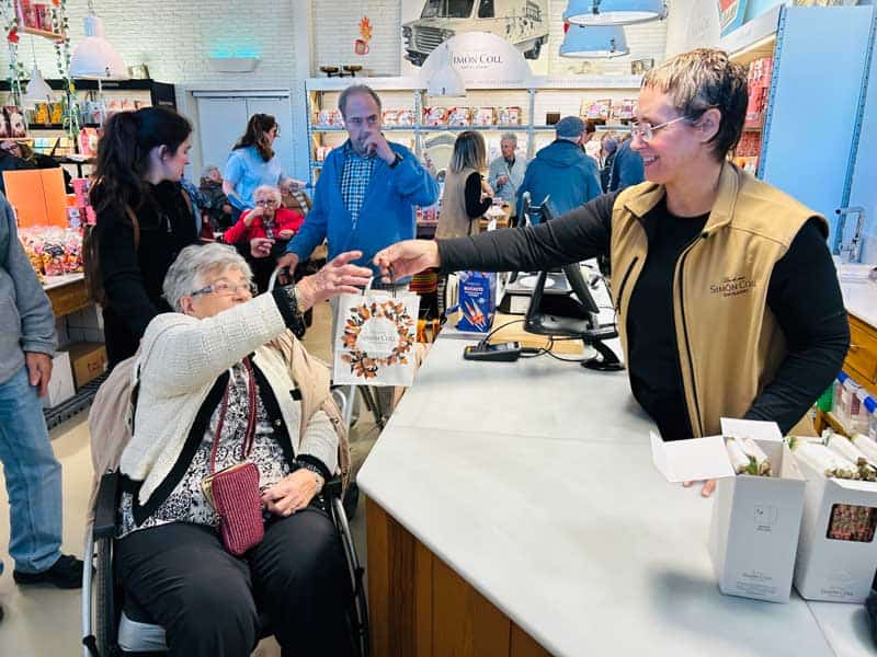 Una residente interactúa con una empleada de la tienda de chocolate