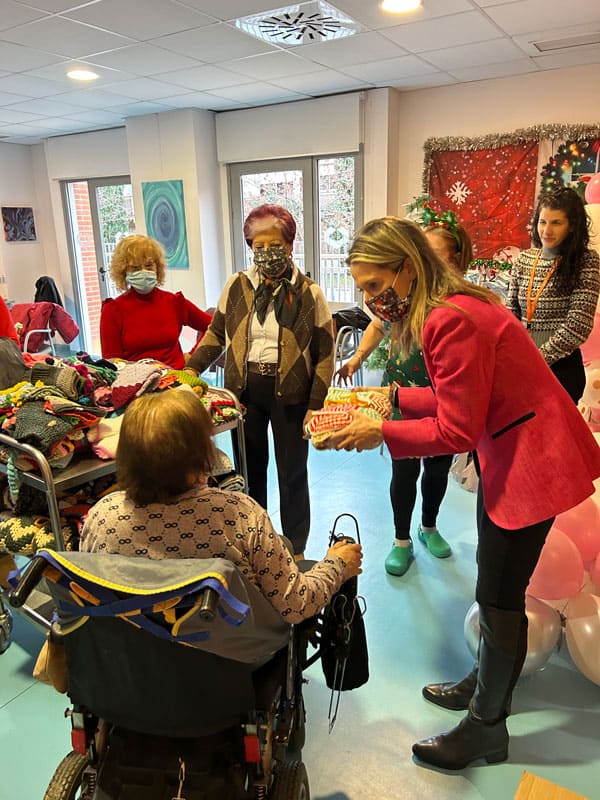 Una visitante entrega un regalo a una residente
