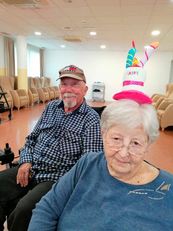 Dos residentes posan sonrientes con el gorro de feliz cumpleaños