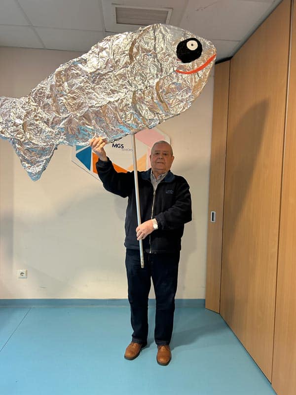 Un residente posa con una manualidad de sardina realizada en el centro