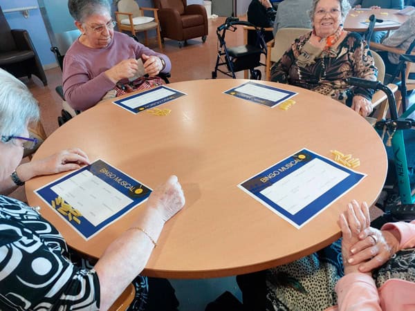 Personas mayores disfrutando de juegos y actividades en un ambiente comunitario en Benviure.