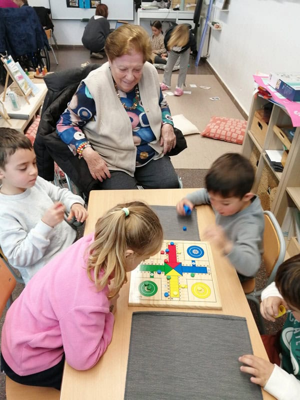 Varios niños y una residente juegan al parchís