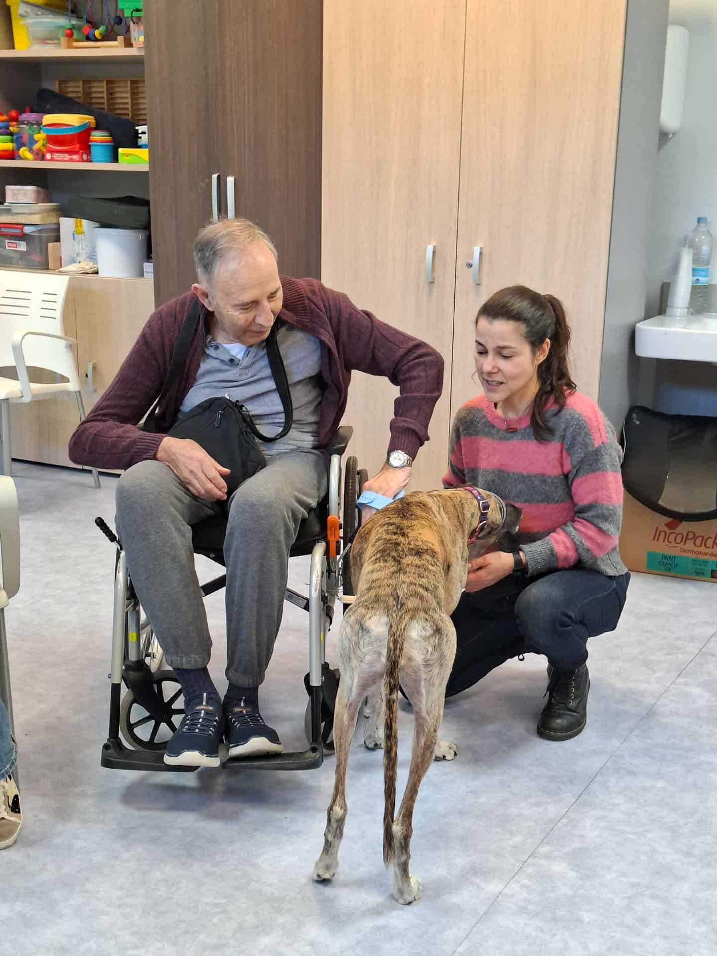 Un residente acaricia feliz al galgo de terapia