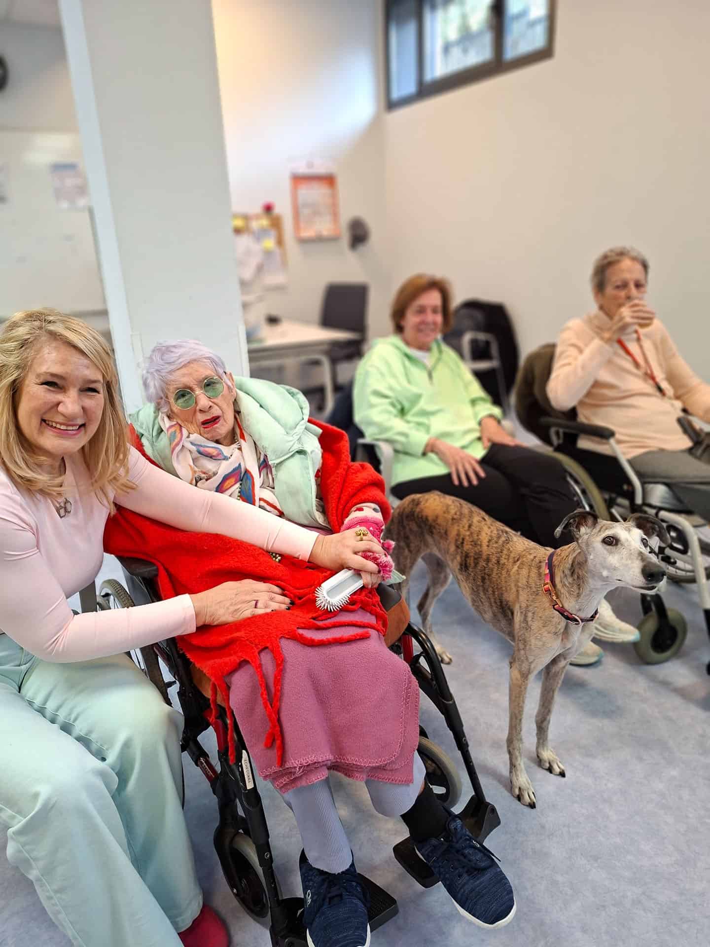 Un grupo de residentes posa feliz junto al galgo