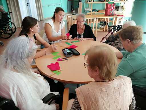 Jóvenes ayudan a residentes a realizar sus rosas artesanales