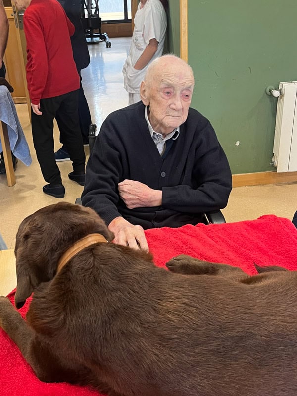 Un residente de Riosol acaricia a un perro de terapia