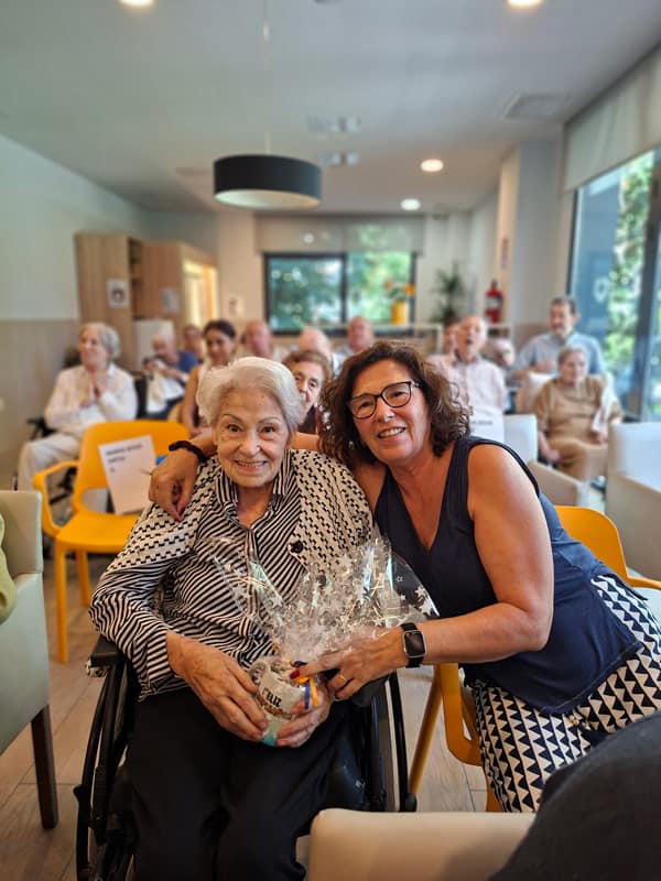 Una residente posa feliz junto a una familiar en su cumpleaños