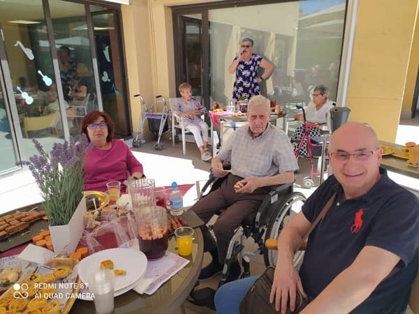 Residentes disfrutan en la sombra del patio de la comida de celebración