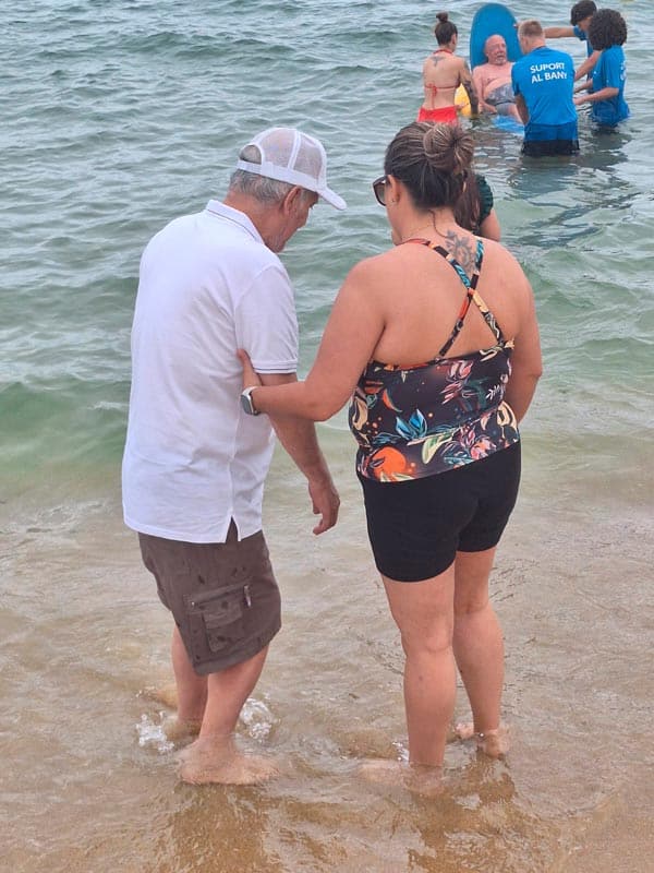 Una auxiliar ayuda a un residente a entrar en el agua