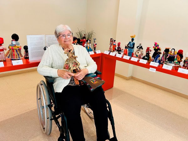 Una residente junto a una de las muñecas de la exposición
