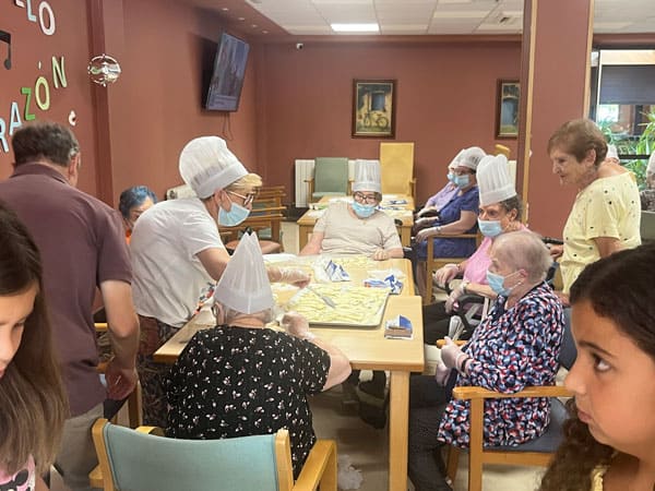 Imagen de los residentes con gorros de cocina y guantes mientras elaboran la receta